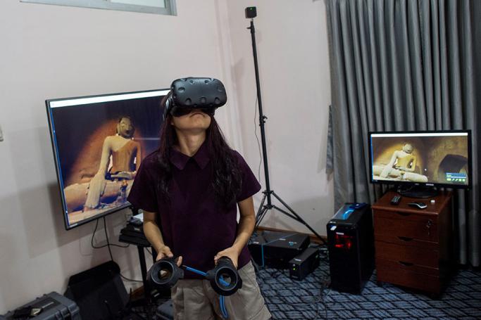 In this photograph taken on August 11, 2017, a woman wears VR goggles as she watches some of the 360˚ 4K video footage that a specialized company recorded at the ancient city of Bagan and its crumbling 700-year-old buildings, while visiting the office of Nyi Lin Seck during an open house visual event in Yangon. Few countries in the world have experienced such rapid discovery of technology than Myanmar which has leapfrogged from the analogue to digital era in just a few years. Photo: Ye Aung Thu/AFP 