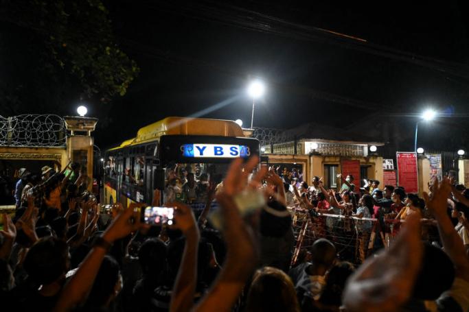Newly-released prisoners wave from a bus as they depart the Insein Prison in Yangon on October 18, 2021, after authorities announced more than 5,000 people jailed for protesting against a February coup which ousted the civilian government would be released. AFP