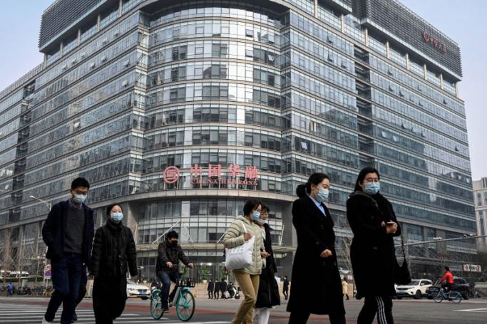People walk past the Huarong Asset Management building in the financial district in Beijing. Photo: AFP 