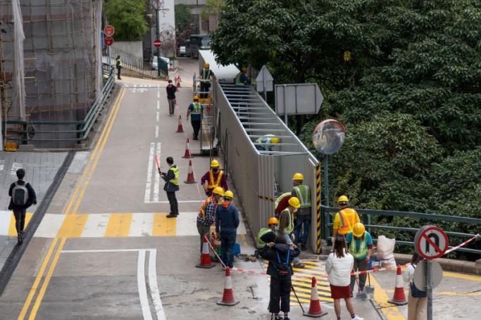 Construction workers use metal sheeting to cover up one of the last public tributes in Hong Kong to the deadly 1989 Tiananmen Square crackdown which has adorned a campus footbridge at the University of Hong Kong (HKU) for over three decades, on January 29, 2022. Photo: AFP