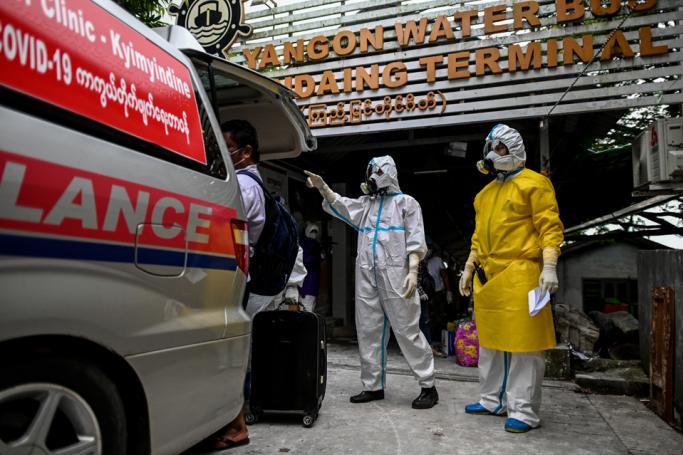 Volunteers wearing personal protective equipment (PPE) watch as people suspected of having the COVID-19 coronavirus get into an ambulance on their way to a quarantine centre in Yangon on October 12, 2020. Photo: Ye Aung Thu/AFP