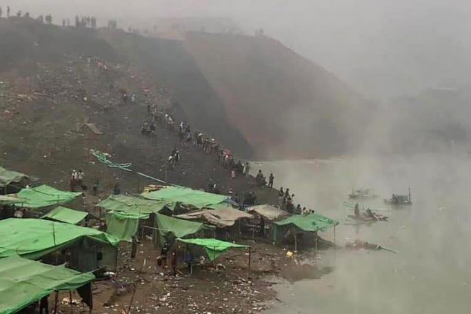 People watch as rescuers prepare to search for missing miners following a landslide at a jade mine in Hpakant, Kachin state on December 22, 2021. (Photo by AFP)
