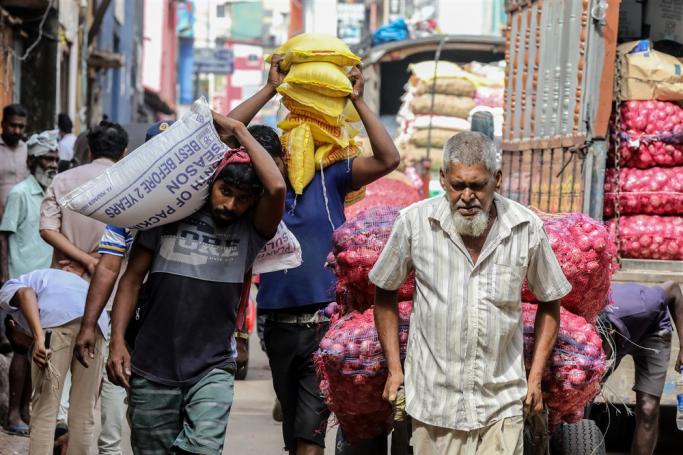 Sri Lankan daily wage workers carry vegetables at a market in Colombo, Sri Lanka. Photo: EPA