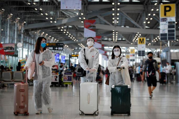 Chinese tourists wearing protective suits, gloves and face masks, walk in the departures hall at Suvarnabhumi international airport in Bangkok, Thailand, 25 March 2020. Photo: EPA