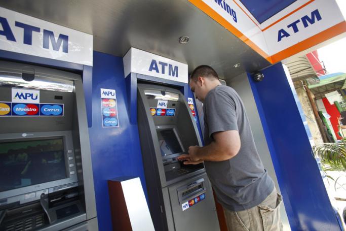 A tourist withdraws money from an ATM machine in Yangon. Photo: Lynn Bo Bo/EPA
