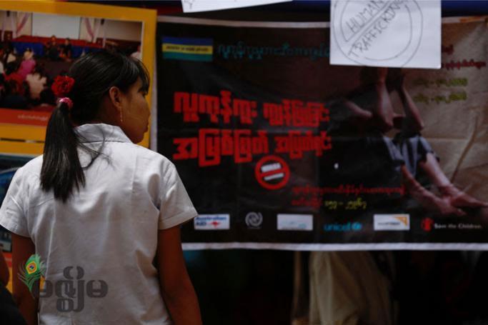 A young woman passes by a billboard campaign to human trafficking in Yangon. Photo: Mizzima