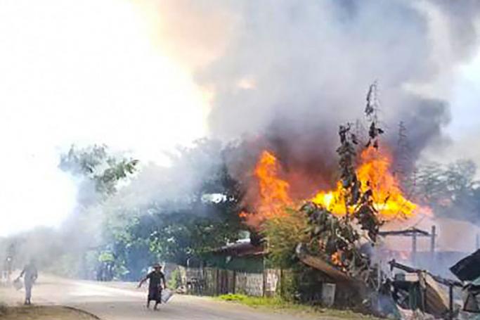 This handout taken on September 10, 2021 and received courtesy of an anonymous source on September 18 shows people attempting to extinguish a fire as houses burn in Namg Kar village in Magwe region's Gangaw township, as fighting continues between the Myanmar military and protesters against the military coup. Handout / ANONYMOUS / AFP