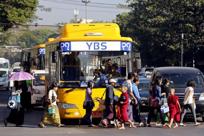 People walk in front of a YBS bus at a traffic light during rush hour in Yangon. Photo: EPA