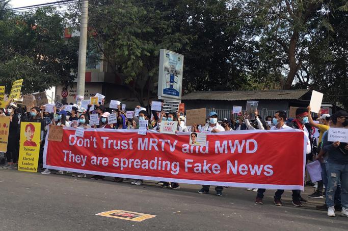 Protesters hold a large banner alleging that the MRTV and MWD media channels spread "fake news" during a demonstration against the military coup in front of the Chinese embassy in Yangon on February 12, 2021. Photo: AFP