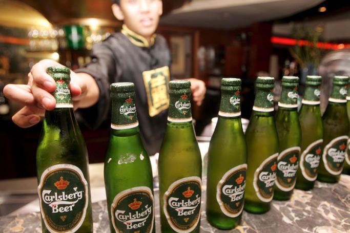 A bar employee lines up Danish Carlsberg beer bottles at a bar in Jakarta. Photo: EPA/WEDA
