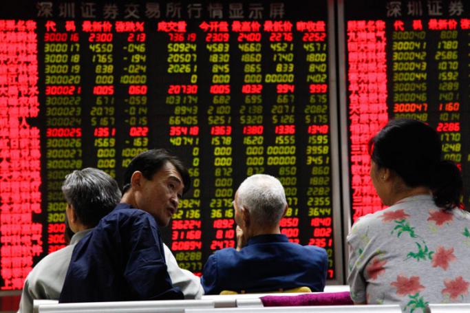An investor (L) talks to a fellow investor while stock market data are displayed on an electronic board at a securities brokerage house in Beijing, China, 18 September 2015. Photo: Rolex Dela Pena/EPA
