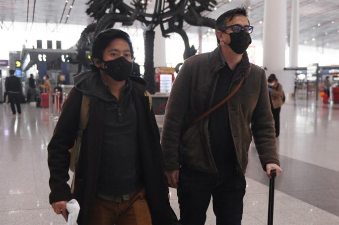 This file photo taken on February 24, 2020 shows Wall Street Journal reporters Josh Chin (R) and Philip Wen walking through Beijing Capital Airport before their departure. (Photo by GREG BAKER / AFP) 