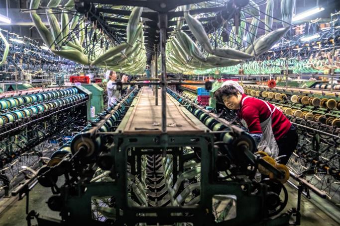 A woman works in a silk clothing factory on modern production machinery for silk clothing in Shengze, Jiangsu province, China. Photo: EPA