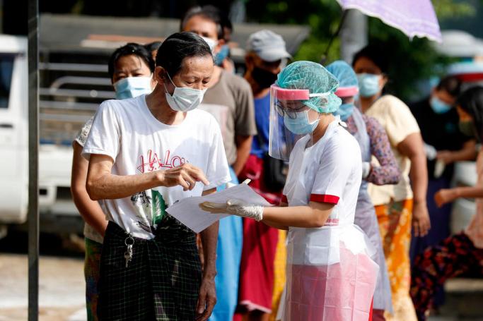A nurse (R) with PPE (Personal protective equipment) checks the personal information of a patient during a medical check-up campaign in Yangon, Myanmar, 23 May 2020. Photo: Nyein Chan Naing/EPA