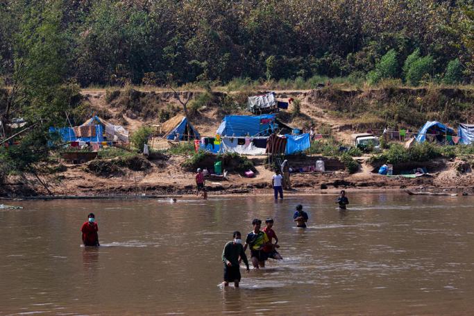 This photo taken on January 15, 2022 shows Myanmar refugees, who fled a surge in violence as the military cracks down on rebel groups, walking across the river on the Thai border as pictured from Thailand's Mae Sot district. Photo: AFP