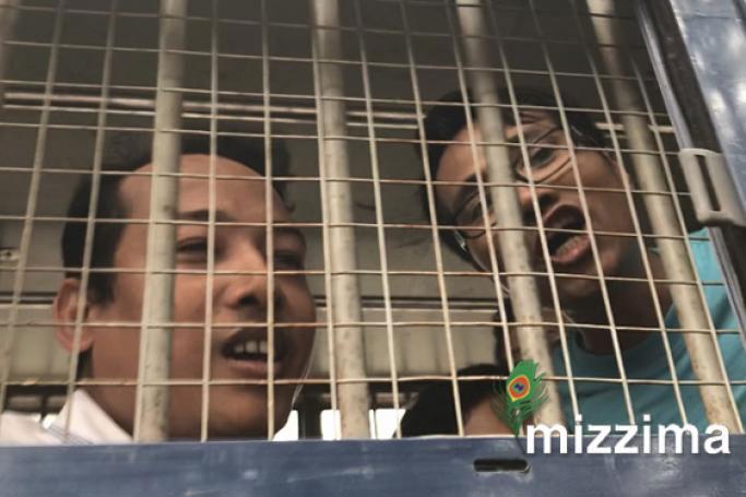 Two of the accused try to talk to reporters from a police van. Photo: Mizzima