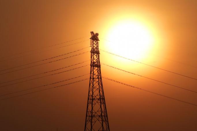 The sun sets behind the electric tower in Yangon. Photo: Lynn Bo Bo/EPA
