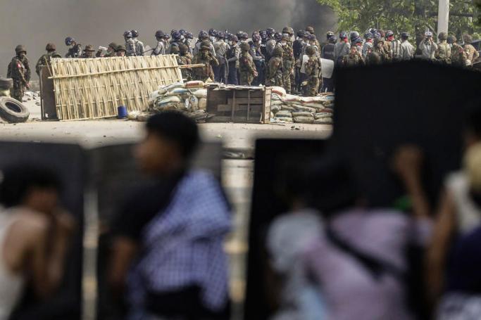 Demonstrators takes cover behind metal shields during a protest against the military coup in Hlaingthaya (Hlaing Tharyar) Township, outskirts of Yangon, Myanmar, 14 March 2021. Photo: EPA