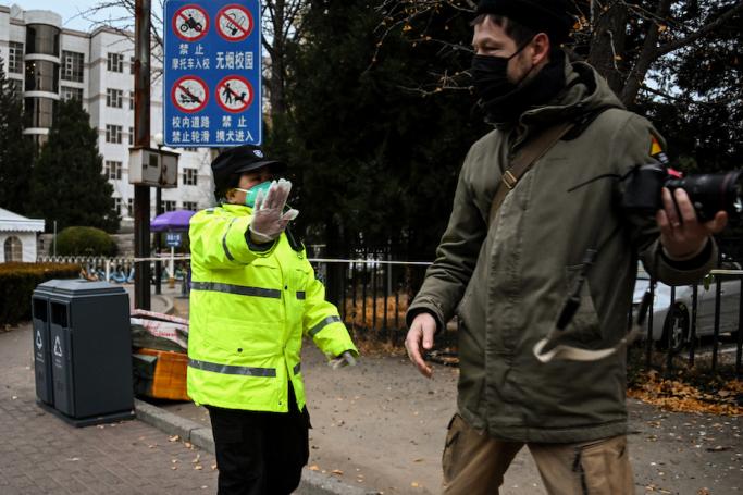 A security guard stops a journalist from taking pictures in front of the entrance gate of the Tsinghua University in Beijing on November 27, 2022. Photo: AFP