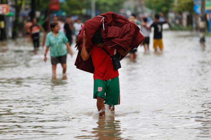  (File) A man carrying monks saffron robes on his head makes his way through flooded road in Mawlamyine, Mon State, Myanmar, 10 August 2019. Photo: Lynn Bo Bo/EPA