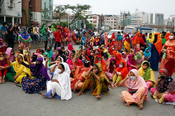 Bangladeshi garment workers, some wearing protective face masks, block a road during a protest to demand payment of wages in Dhaka, Bangladesh, 15 April 2020. Photo: EPA
