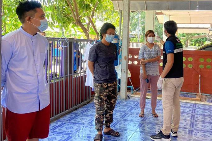 In this photo released by the San Sai District Administrative Office, a Thai officer checks the temperature of journalists working for Democratic Voice of Burma, at San Sai District in Chiang Mai province north of Thailand Sunday, May 9, 2021. 
