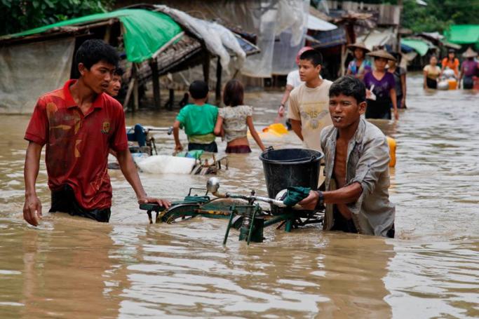 A picture made available on 04 August 2015 shows people carrying their belongings as they pass through a flooded street in Min Pyar township of Rakhine State, Myanmar, 02 August 2015. Photo: Nyunt Win/EPA
