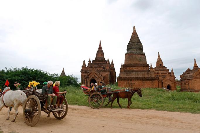 Foreign tourists ride on bullock carts and a horse-drawn carriage in Bagan. Photo: Rungroj Yongrit/EPA
