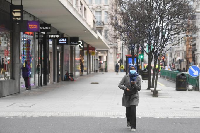 Masked people pass shuttered stores on Oxford Street in London, Britain. Photo: EPA