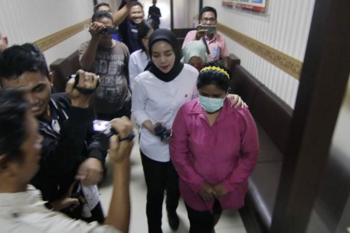 Two women (front R in pink and middle R in green, partly obscured), arrested for allegedly posting misinformation online relating to coronavirus, are being escorted for a police press conference in Balikpapan. Photo: AFP