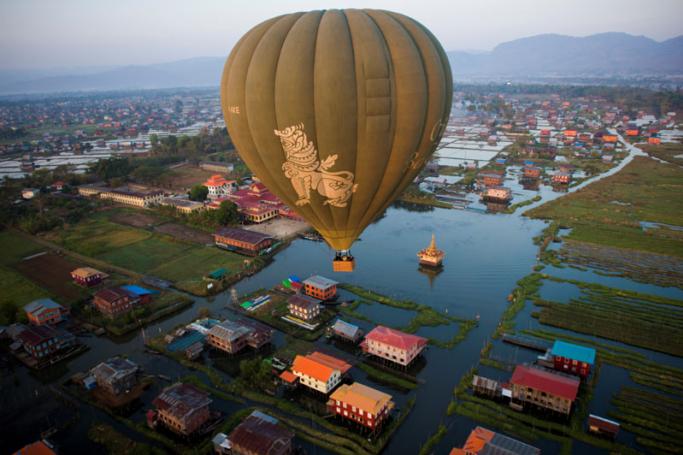 This aerial photo taken from a hot air balloon shows a hot air balloon flying over traditional houses on stilts on Inle lake in Shan State. Photo: Ye Aung Thu/AFP
