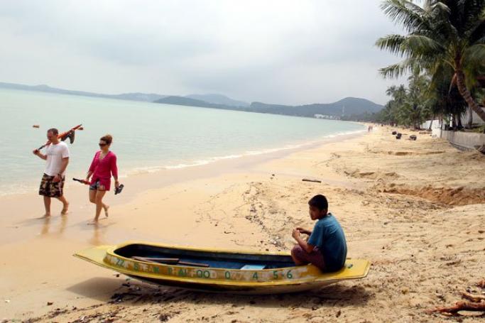 The murder of the Myanmar migrant worker took place at a popular ocean viewpoint. Foreign tourists walk past a Thai boy on the resort island of Koh Samui, Surat Thani province, southern Thailand, April 1, 2011. Photo: Rungroj Yongrit/EPA
