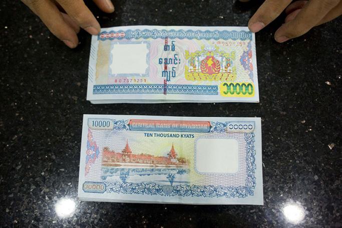 An employee shows new ten thousand Myanmar Kyat notes at a bank in Yangon. Photo: AFP