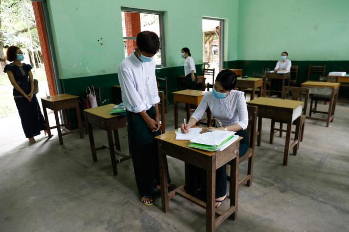  A students (C-L) stands near a teacher (C-R) during the registration to attend a class at a school in Yangon, Myanmar, 17 July 2020. Photo: Lynn Bo Bo/EPA