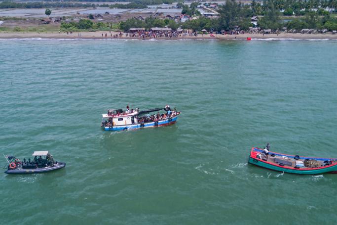 This aerial picture shows a wooden boat (C) carrying Rohingya from Myanmar being pulled away from the shoreline near Lancok village in Indonesia's North Aceh Regency on June 25, 2020. Photo: AFP