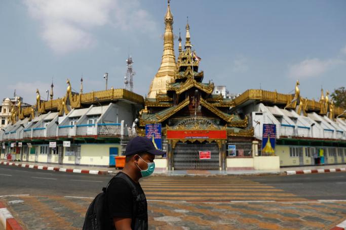 A man wearing a mask walks past Sule pagoda in downtown Yangon, Myanmar, 29 March 2020. Photo: Lynn Bo Bo/EPA