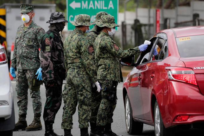 A Filipino soldier uses a thermal scanner to check the temperature of motorists entering the metropolis at a checkpoint on SLEX entry point of San Pedro City, Philippines, 16 March 2020. Photo: EPA