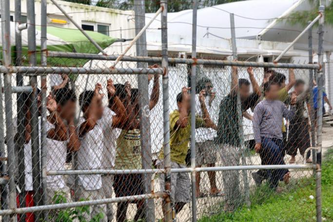 A picture dated 21 March 2014 and made available on 27 April 2016 shows asylum seekers staring at media from behind a fence at the Oscar compound in the Manus Island detention center, Papua New Guinea. Photo: Eoin Blackwell/EPA
