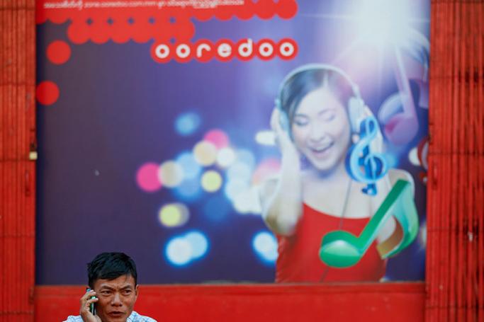 A man speaks on his mobile phone in front of a building with Ooredoo telecom advertising at downtown area in Yangon, Myanmar, 09 February 2016. Photo: Lynn Bo Bo/EPA
