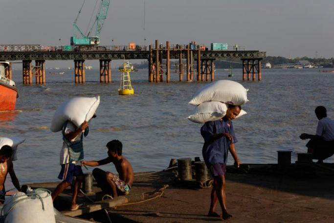 Myanmar labourers load rice bags on their shoulders as they work at a jetty of Yangon river, in Yangon, Myanmar. Photo: Lynn Bo Bo/EPA