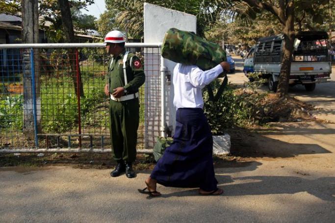 Allegations have been made that a 17-year-old boy was forced to join the military. Here, a boy wearing white shirt (R), who was discharged from the Myanmar army, walks past a security official as he leaves after the ceremony of handover for discharged minors to parents or guardians in Yangon, Myanmar, January 18, 2014. Photo: Lynn Bo Bo/EPA
