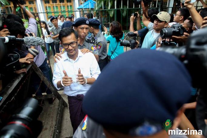 Editor in chief of Eleven media Kyaw Zaw Linn (C), escorted by police gestures in handcuffs as he arrives Tamwe township court in Yangon on 10 October 2018. Photo: Thura/EPA