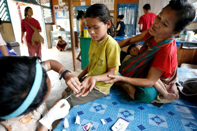 A Karen health worker (L) takes a blood sample from a local girl (C) for a Malaria check at the Paw Bu La Hta clinic in Kow Poe Kee village, Karen state. Photo: Rungroj Yongrit/EPA