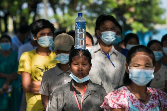 A woman with a bottle of water on her head wait with other voters outside a polling station in Yangon on November 8, 2020. Photo: Sai Aung Main/AFP