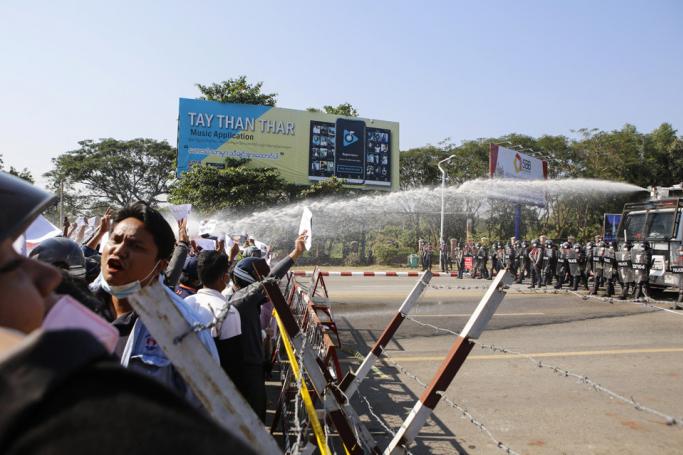 Myanmar police (R) fire water cannon at protesters as they continue to demonstrate against the February 1 military coup in the capital Naypyidaw on February 9, 2021. Photo: AFP