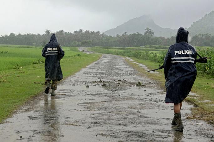 Myanmar police officers in rain coats patrol on a road in the etnic Rakhine village of ChainKharLi, an area close to fighting at Rathedaung township of northern Rakhine State, western Myanmar, 26 August 2017. Photo: Nyunt Win/EPA
