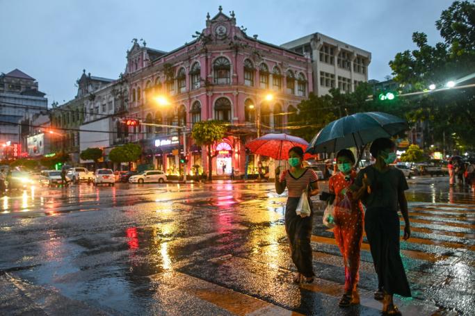 People holding umbrellas as they cross a road during rainfall in Yangon. Photo: Ye Aung Thu/AFP