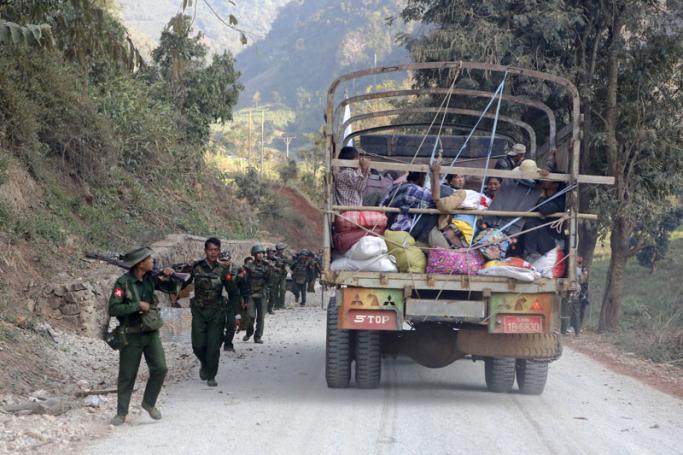 A rescue truck loaded with fleeing locals passes armed military troops near self-administered Kokang capital Laukkai, northern Shan State, Myanmar, 17 February 2015. Photo: Lynn Bo Bo/EPA
