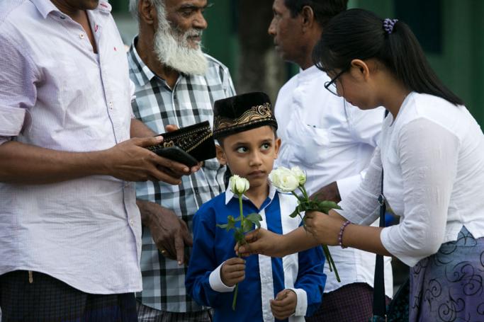 A Buddhist woman gives a white rose to a Muslim boy after he completed prayers during Eid al-Fitr at Than Lyin township on the outskirts of Yangon on June 5, 2019. Photo: Sai Aung Main/AFP