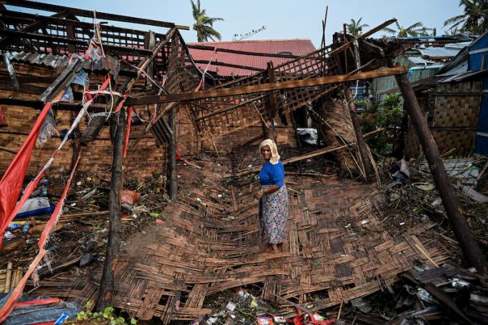 A Rohingya woman stands in her destroyed house at Basara refugee camp in Sittwe on May 16, 2023, after cyclone Mocha made a landfall. Photo: AFP